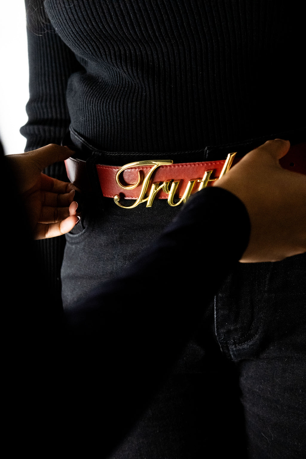 Person wearing a black sweater with a red belt featuring gold lettering. Belt of Truth in Red - Christian belt. LOVE GOD BIG Christian streetwear clothing brand. New Zealand Faith-based apparel. New Zealand. Front.