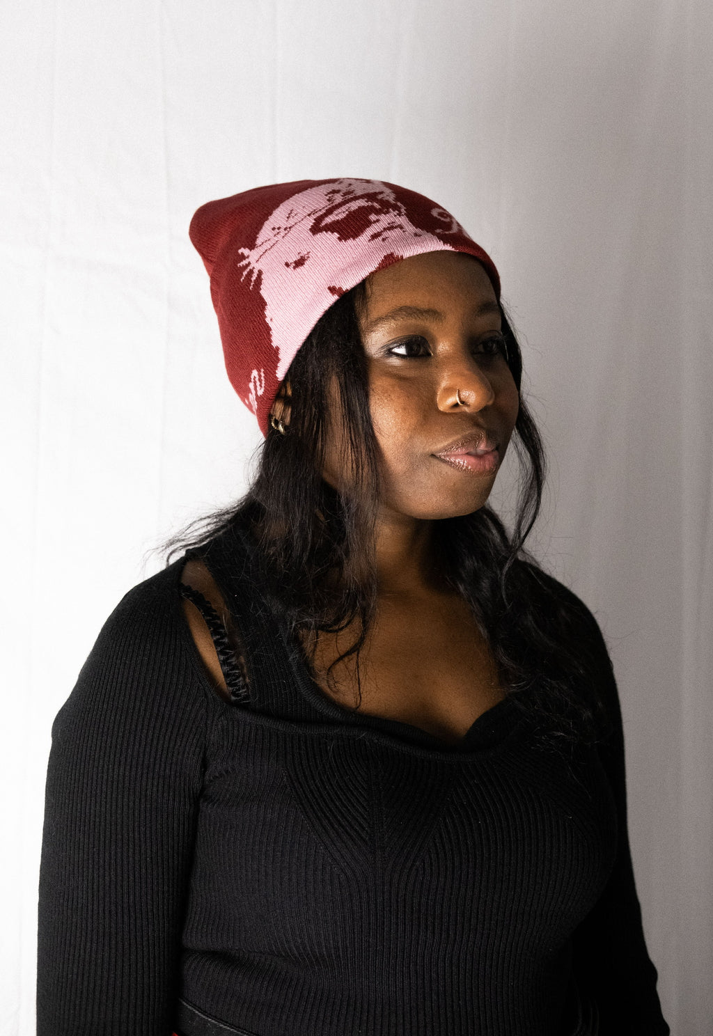 Woman wearing a red beanie with a white design on a plain background. Helmet of Salvation. LOVE GOD BIG Christian clothing brand streetwear faith-based apparel.
