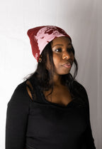 Woman wearing a red beanie with a white design on a plain background. Helmet of Salvation. LOVE GOD BIG Christian clothing brand streetwear faith-based apparel.