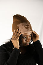 Person wearing a brown helmet of salvation beanie. Front. Close-up. LOVE GOD BIG Christian clothing brand streetwear faith-based apparel.