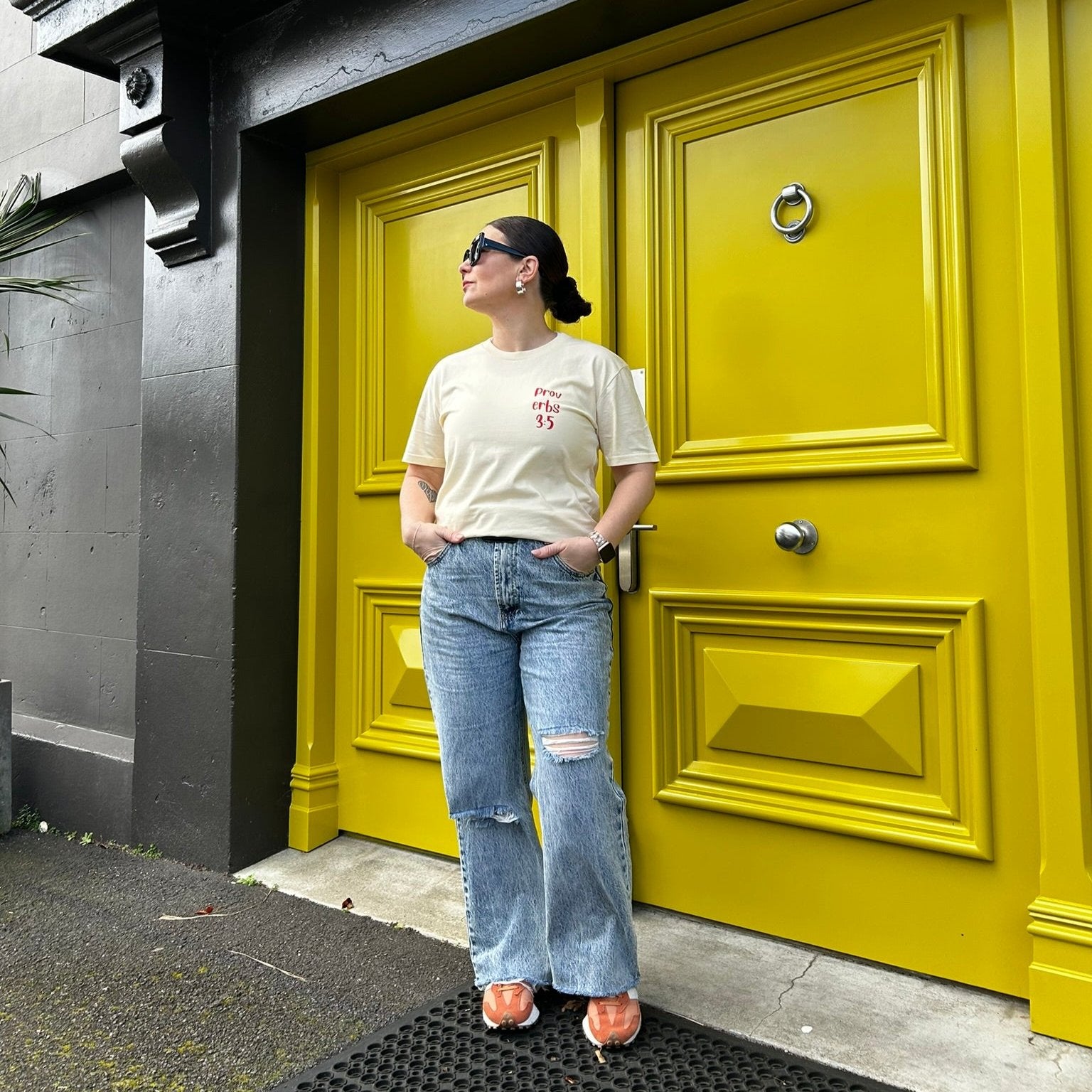 Person wearing Proverbs 3:5 Tee in Cream with red heart. Christian clothing printed in New Zealand. Front side. Streetwear. Stylish. Fashionable. Faith-based apparel. Love God Big. 