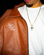 Person wearing a brown leather jacket with 'Love God Big' text and a white t-shirt.
