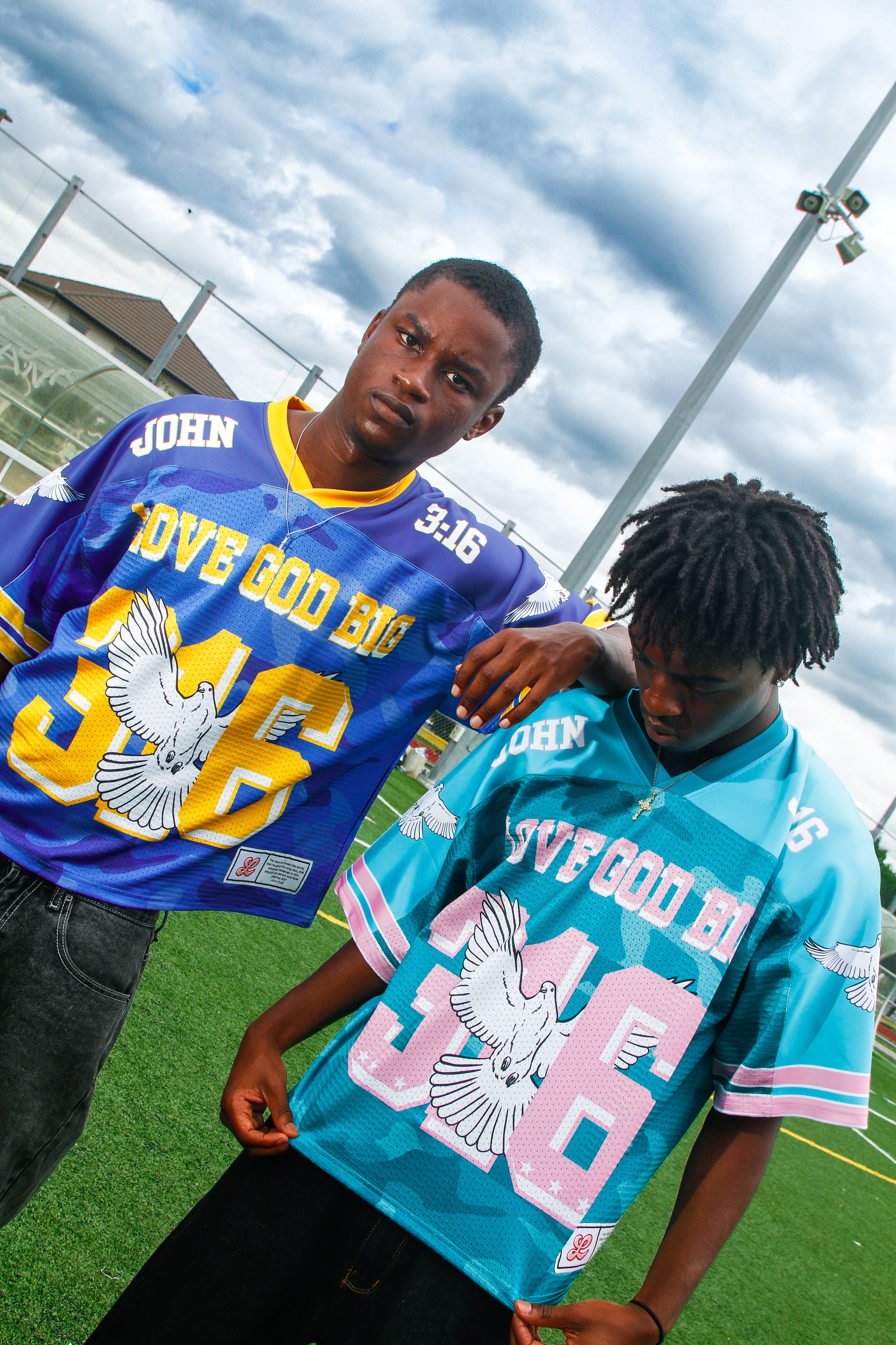 Two models wearing the Saviour Football Jersey in Blue and Green from LOVE GOD BIG. Front. Designed in New Zealand.