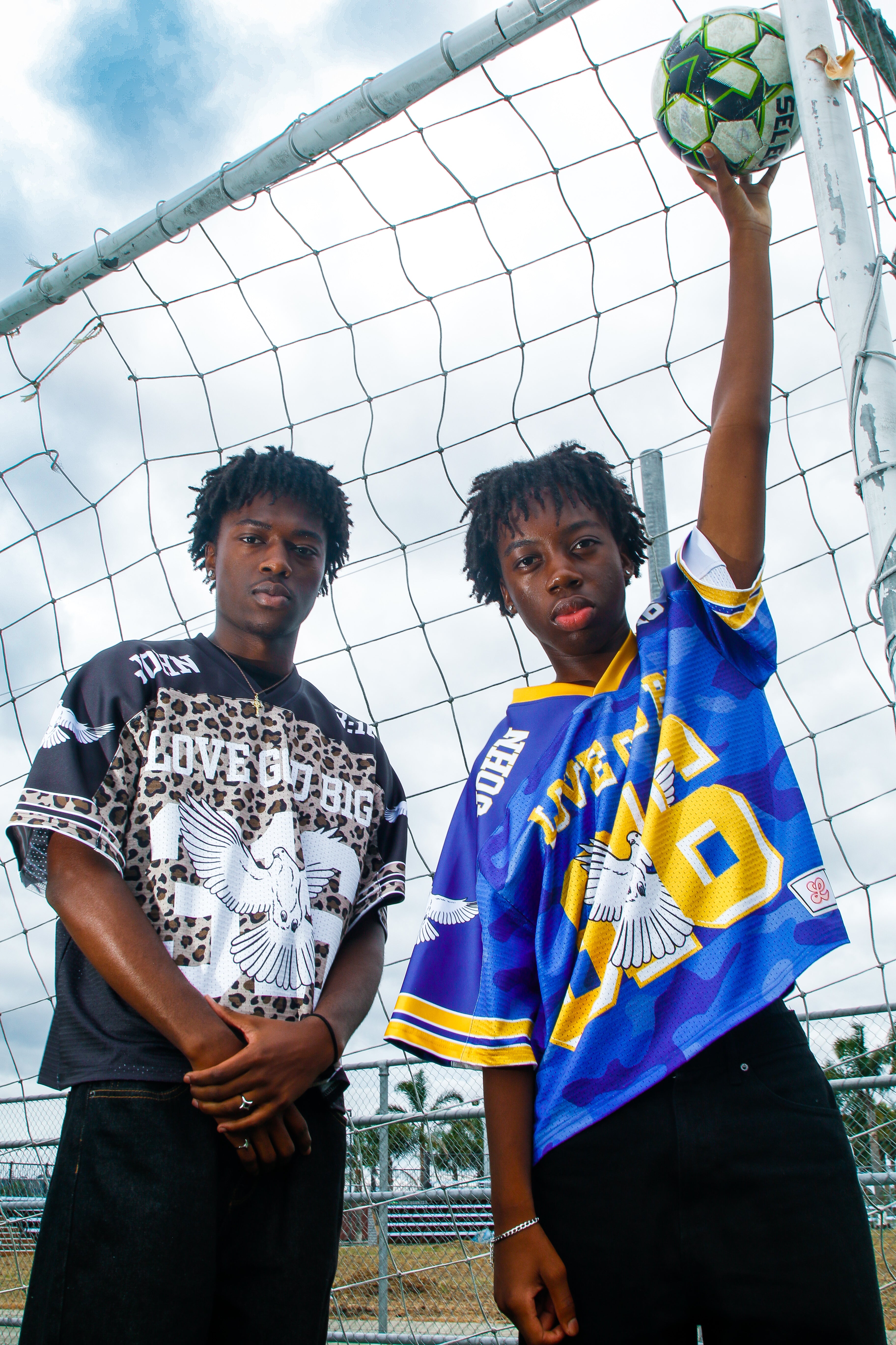 Two models wearing Saviour Football Jersey in black and blue from LOVE GOD BIG. Front. Designed in New Zealand.
